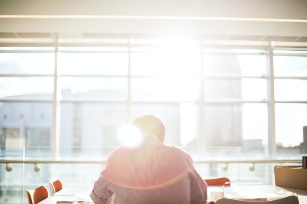 Ein Unternehmer sitzt vor einem Fenster und sieht sich Unterlagen an. Im Beitrag erfährst du, wie du die Digitalisierung des B2B-Vertriebs vorantreiben kannst.